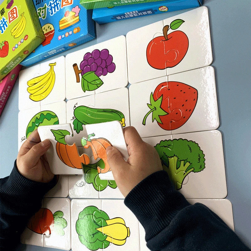 A hand is holding and interacting with a set of square puzzle cards featuring various fruits and vegetables for a toddler mat