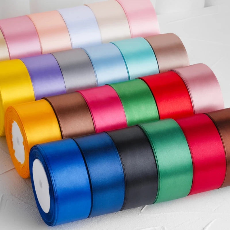A collection of rolled satin ribbon in various colors including pink, blue, green, yellow, and red.