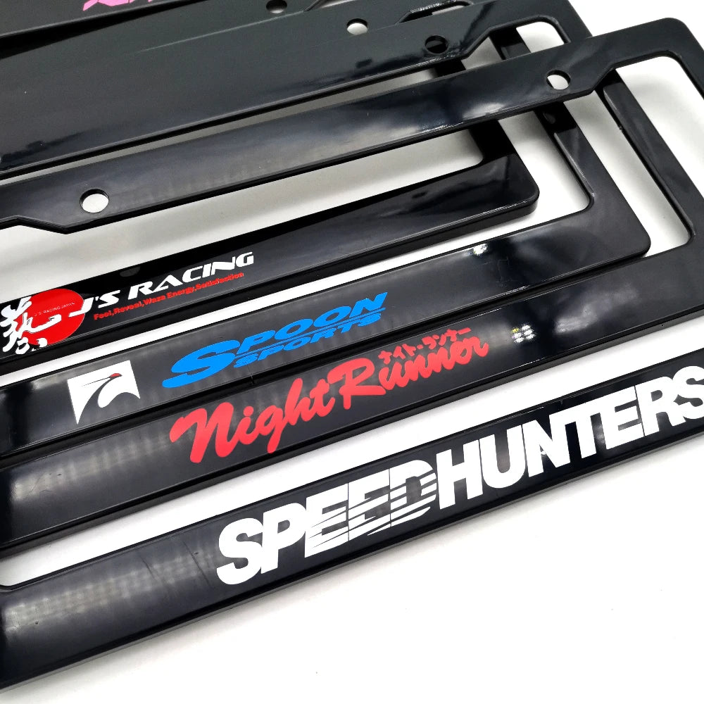 A pair of black racing style license plate frames featuring various text designs like Spoon Sports and Night Runner.