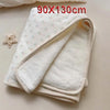 A white floral muslin baby blanket folded and displayed on a light surface.