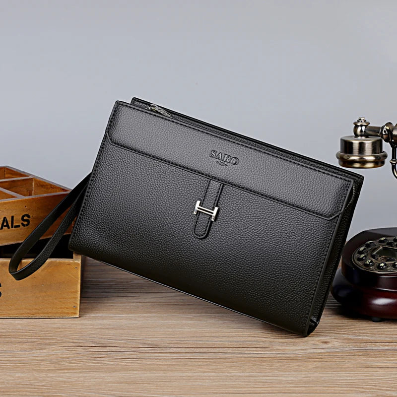 Schwarze Damen-Clutch aus Kunstleder mit silberner Hardware auf Holzoberfläche.