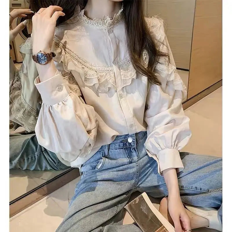 A woman models a cream vintage lace long sleeve blouse and blue jeans.
