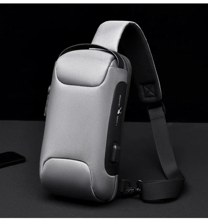 Bolso cruz gris para hombre multifuncional antirrobo con correa negra, mostrado contra fondo oscuro.