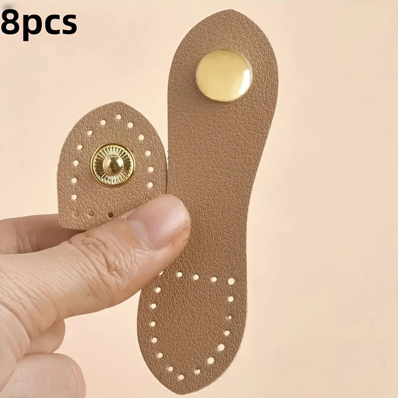 Eight brown leather buckle clasps with gold accents shown being held by a hand