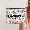 A hand holds a colorful canvas charger storage pouch featuring various charging cables and devices.