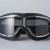 A pair of black retro foldable motorcycle goggles with silver trim are shown against a light gray background.