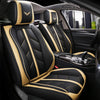 Black car seat covers with tan stitching and gold emblems installed in a vehicle interior.