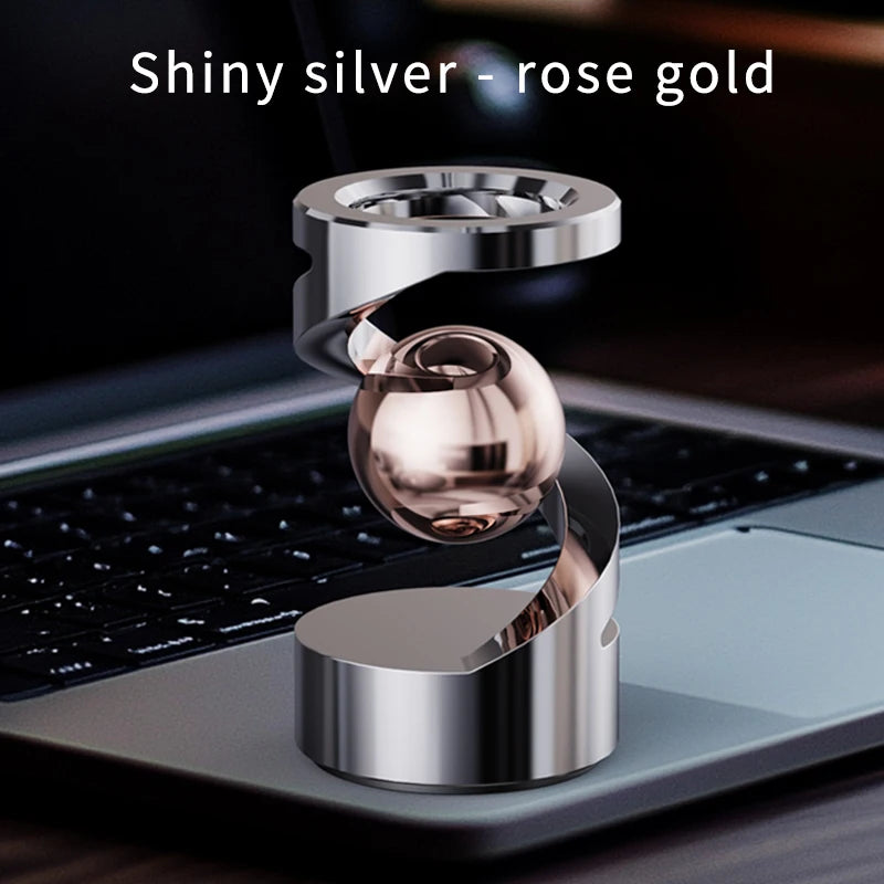 Shiny silver rose gold magnetic levitating spinning top resting on a laptop keyboard
