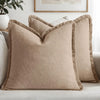 A beige boho fringe throw pillow cover with a natural linen texture resting on a light gray sofa.