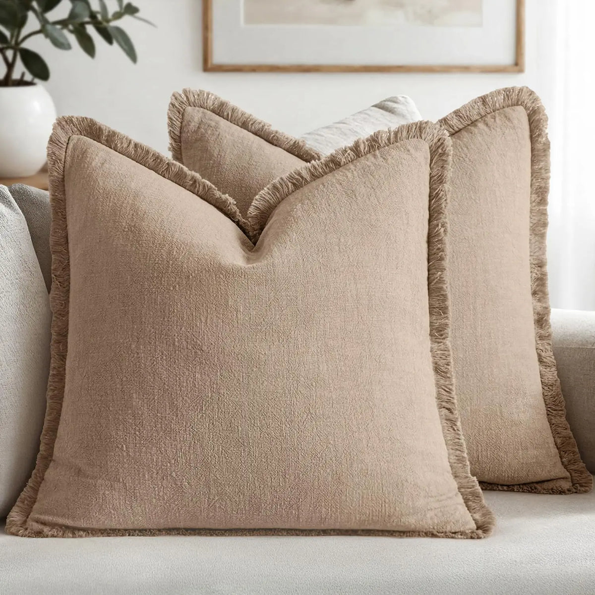 A beige boho fringe throw pillow cover with a natural linen texture resting on a light gray sofa.