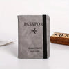 A gray leather passport cover with black stitching and a black strap, featuring the text PASSSPORT and CHARM ETERNITY travel 