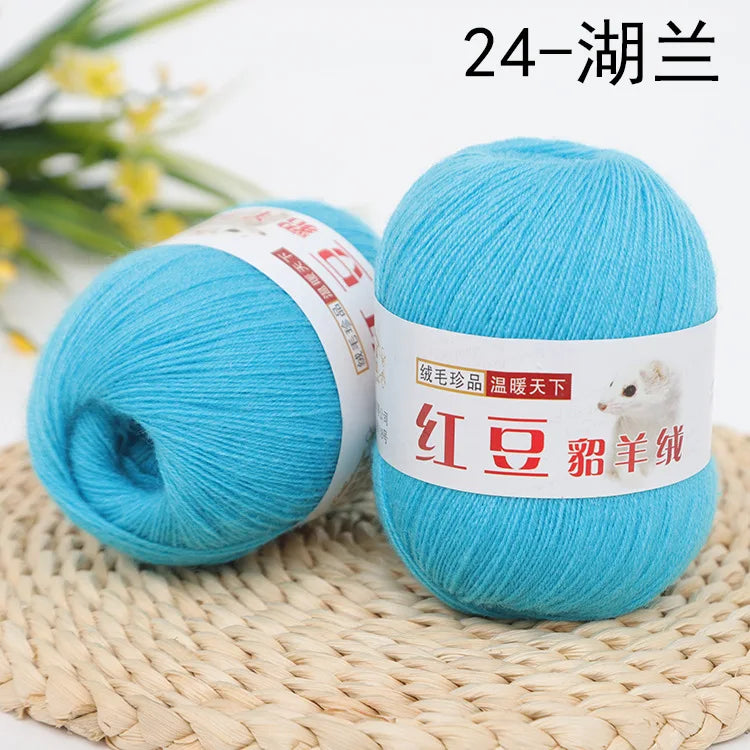 A ball of bright turquoise yarn labeled as 24-strand yarn for knitting and crochet, resting on a woven mat.