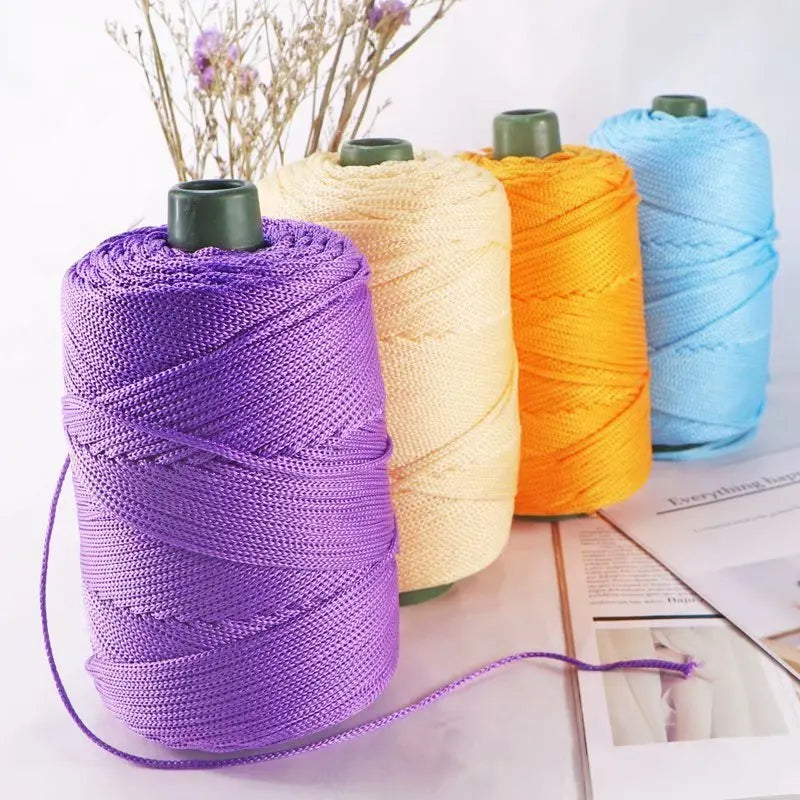 Purple crochet ice rope spool next to yellow and orange colored ropes on a white surface.