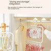 A white laundry drying rack with multiple clips holding pink and white shirts inside a closet.