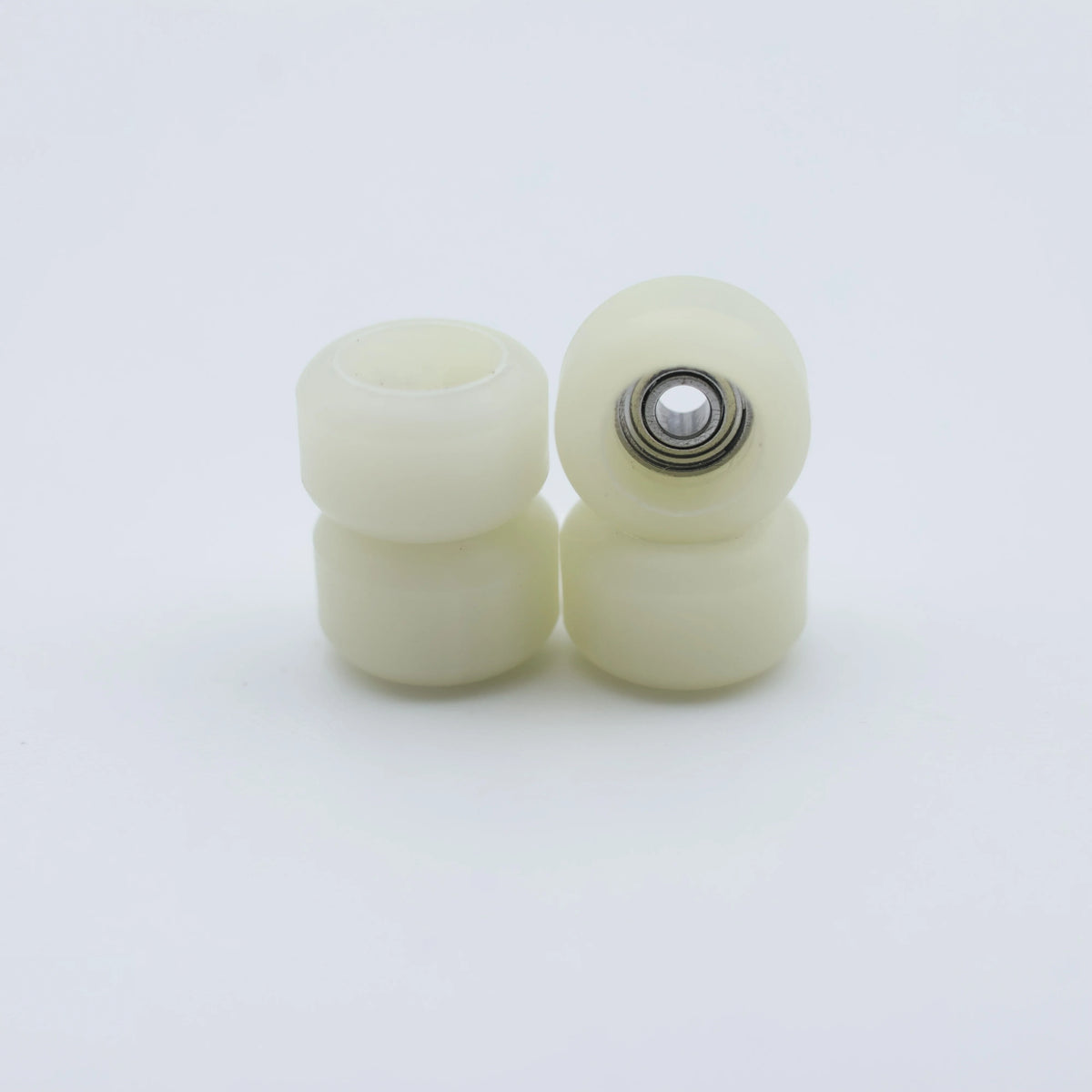 A set of white urethane fingerboard wheels with visible bearings.