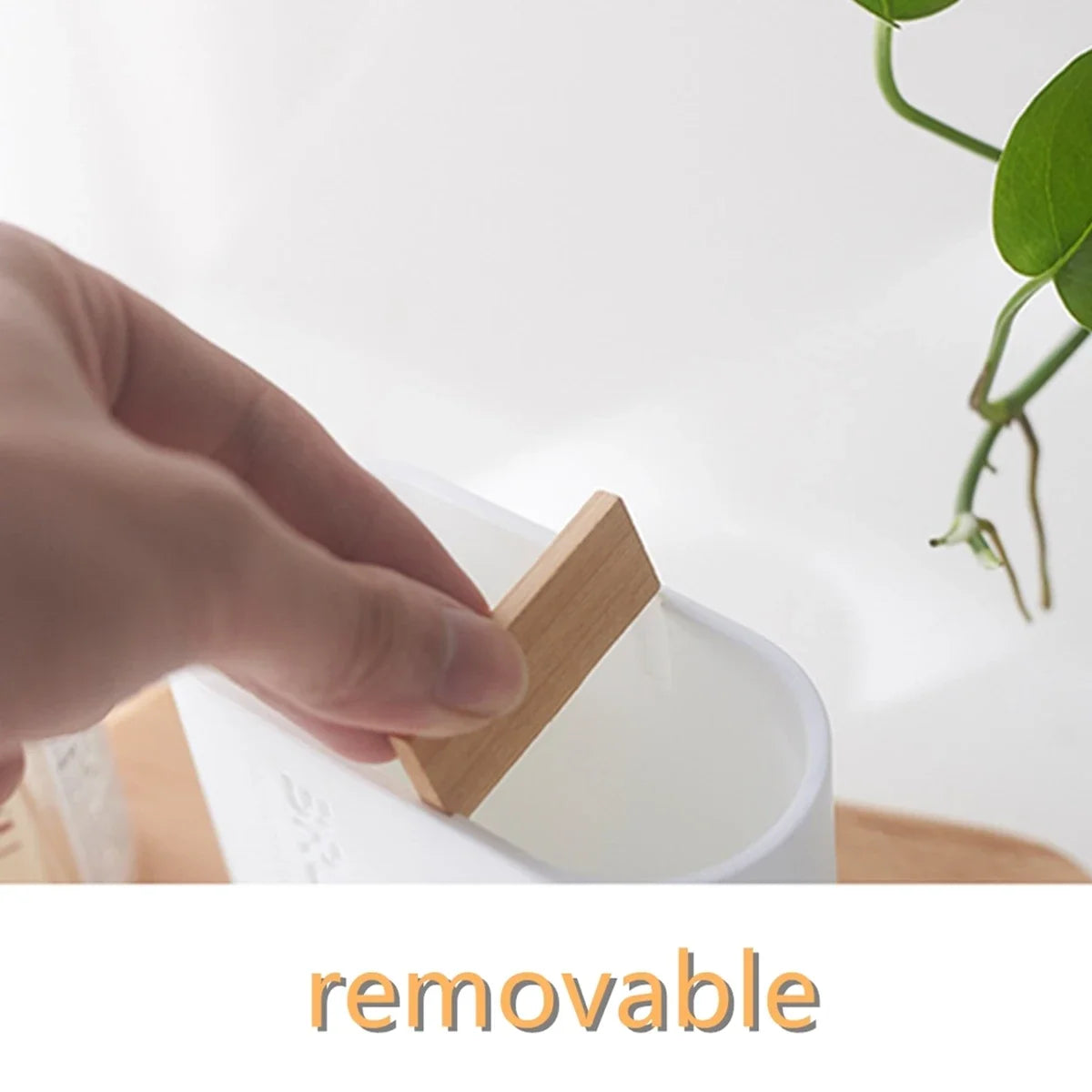 A hand is shown removing a wooden piece from a white bathroom organizer set with a soap dispenser.