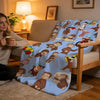A light blue blanket featuring cartoon animals and people in various poses draped over a wooden chair.