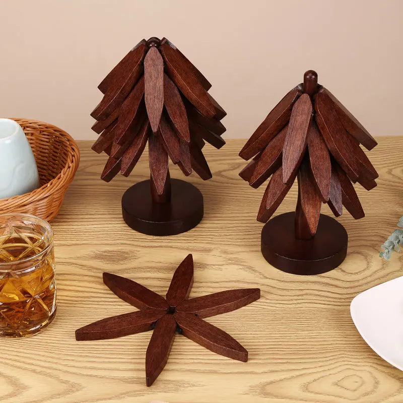 A set of dark brown wooden tree design coasters and folding placemats displayed on a light wood surface.
