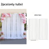 White tulle curtains with pink floral accents shown hanging in a window frame.