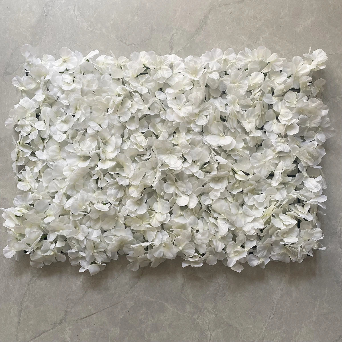 A dense wall panel made of white silk rose flowers for weddings and events