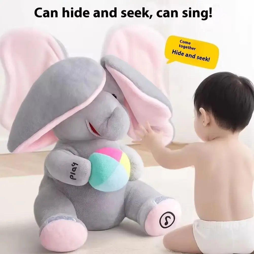 A gray elephant plush toy with pink ears is being played with by a baby.