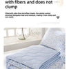 A light blue quilted blanket with a floral pattern is folded on a white surface.