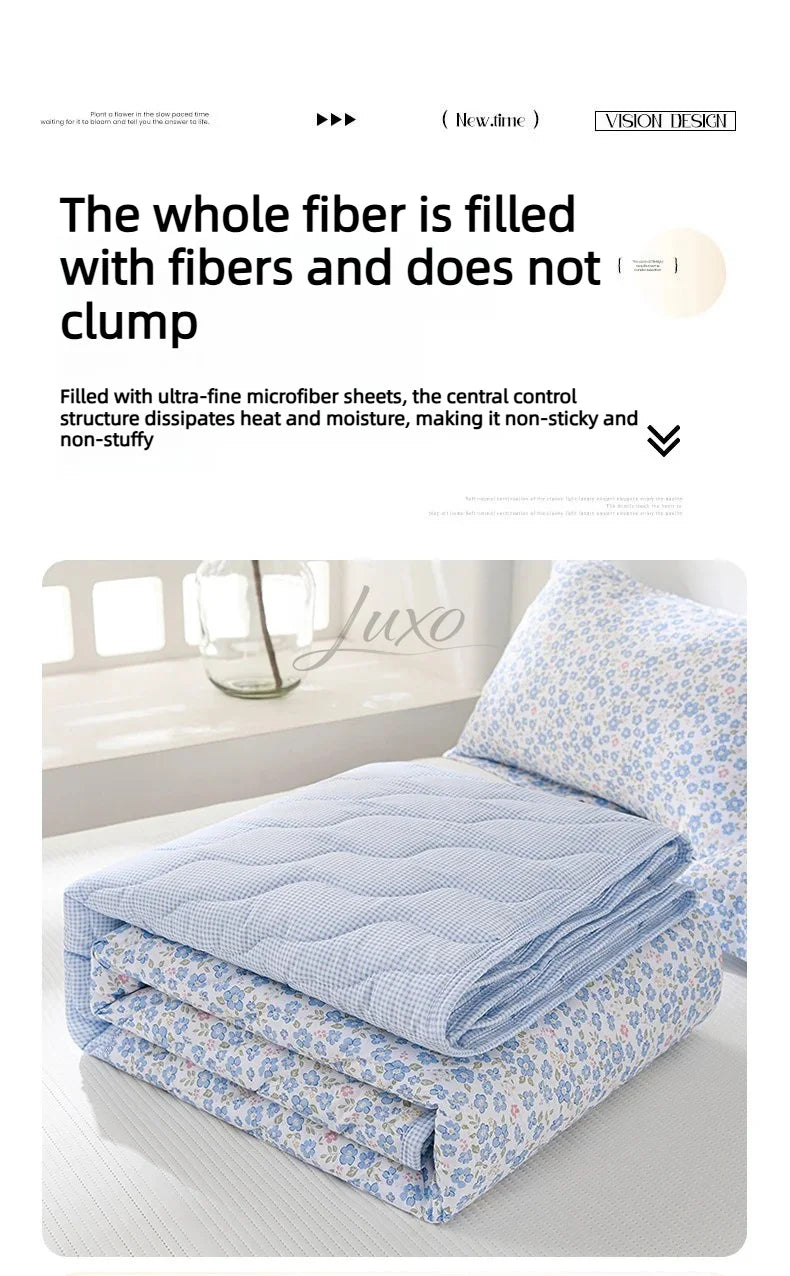 A light blue quilted blanket with a floral pattern is folded on a white surface.