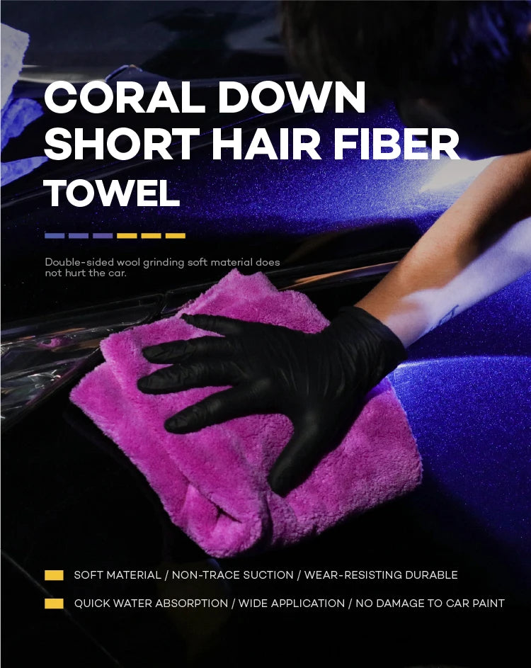 A hand wearing a black glove is using a bright pink coral down short hair fiber towel on a dark car surface.