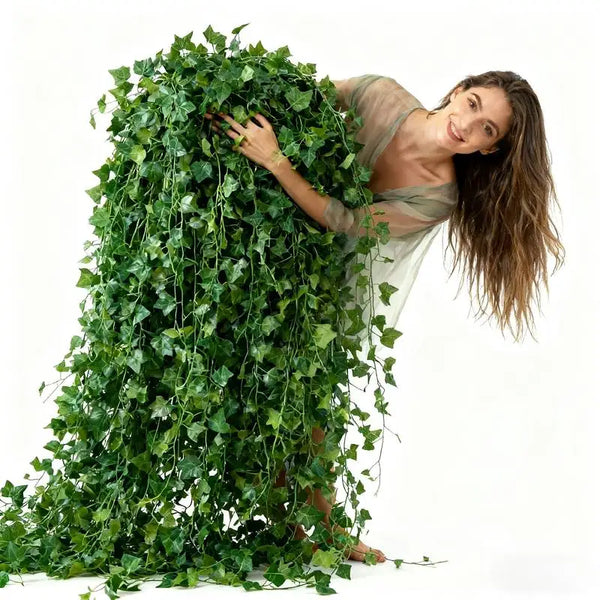 A woman is holding a large garland of green artificial ivy leaves.