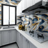 Modern kitchen featuring white cabinets, marble countertops, and blue and gold marbled backsplash tiles.