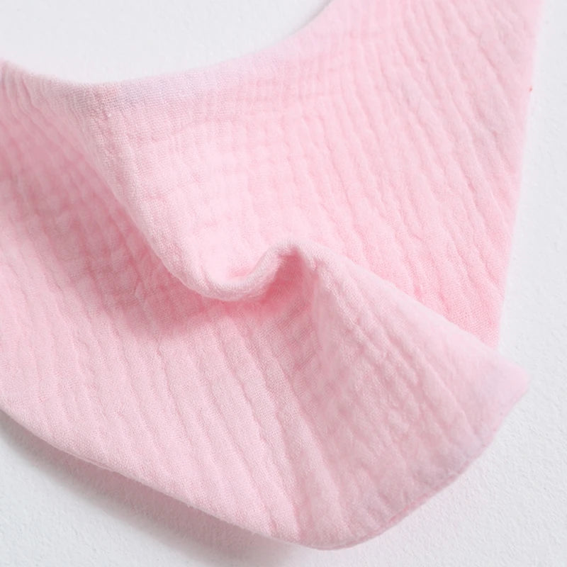 Pink organic cotton muslin baby bibs with an absorbent bandana shown in a close-up fold.