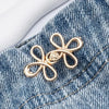 Gold clover-shaped buckle attached to denim fabric