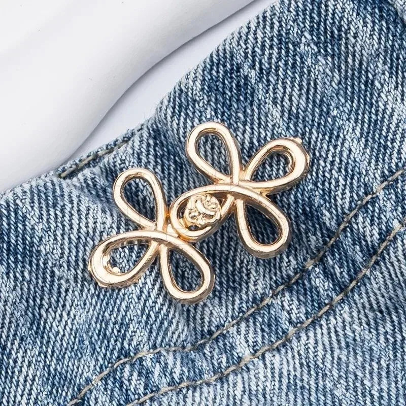 Gold clover-shaped buckle attached to denim fabric