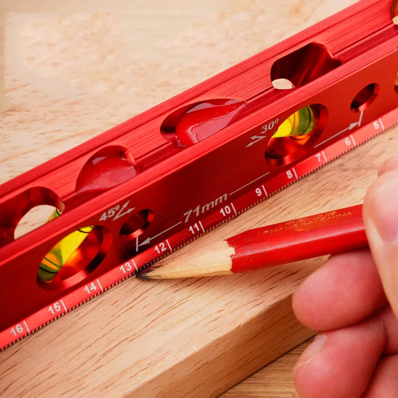 A red magnetic aluminum level ruler with V-grooves is shown next to a pencil on a wooden surface.