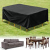 Black waterproof patio furniture cover spread over a table on green grass, next to a wooden dining set.