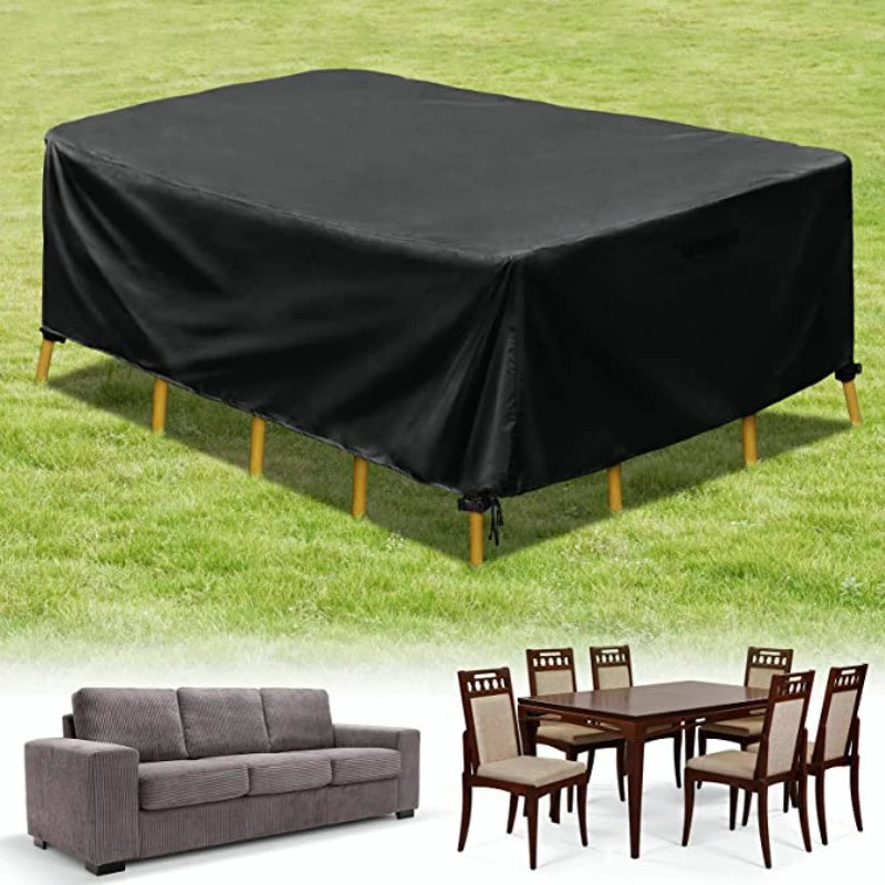 Black waterproof patio furniture cover spread over a table on green grass, next to a wooden dining set.