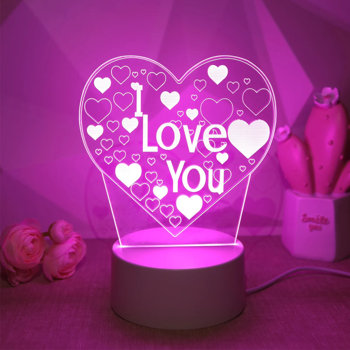 A glowing pink heart LED night light with a white 'I Love You' design displayed on a surface.