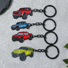 A collection of four die-cast Ford Bronco model cars in red, blue, orange, and yellow, each attached to a black chain keychai