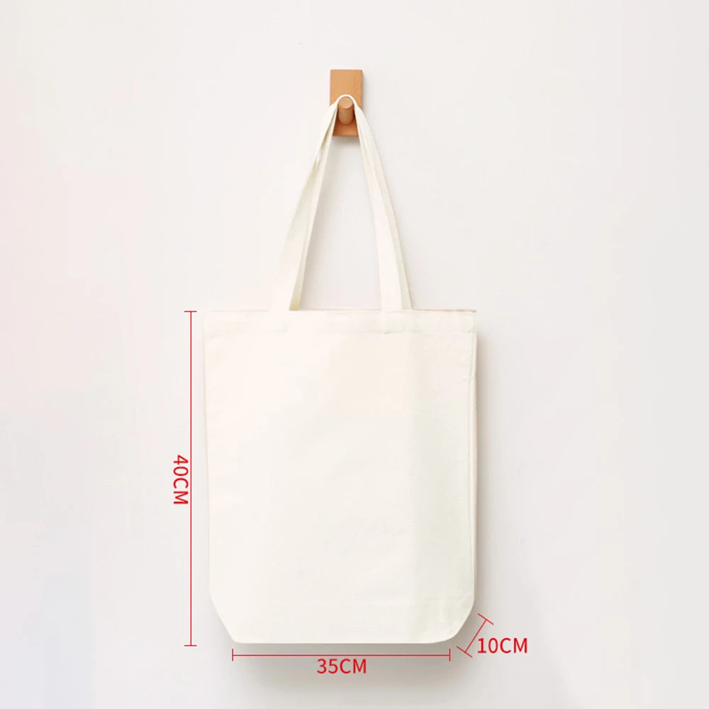 A white reusable canvas shopping tote bag displayed vertically with a wooden hanger.