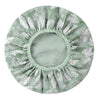 A large, round shower cap with a pleated design featuring a green and white tropical leaf pattern.