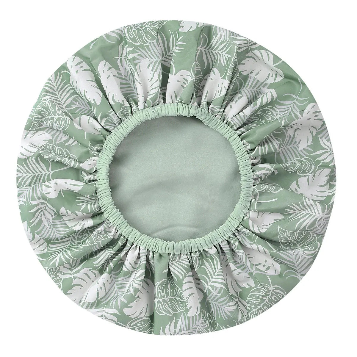 A large, round shower cap with a pleated design featuring a green and white tropical leaf pattern.