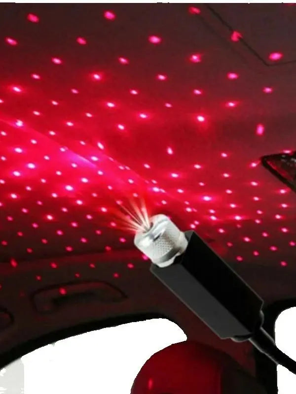 A portable LED projection lamp is shining red light onto the ceiling of a car interior.