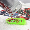 A transparent storage bag is pouring red and silver sequins onto a green plastic tray on a white surface.