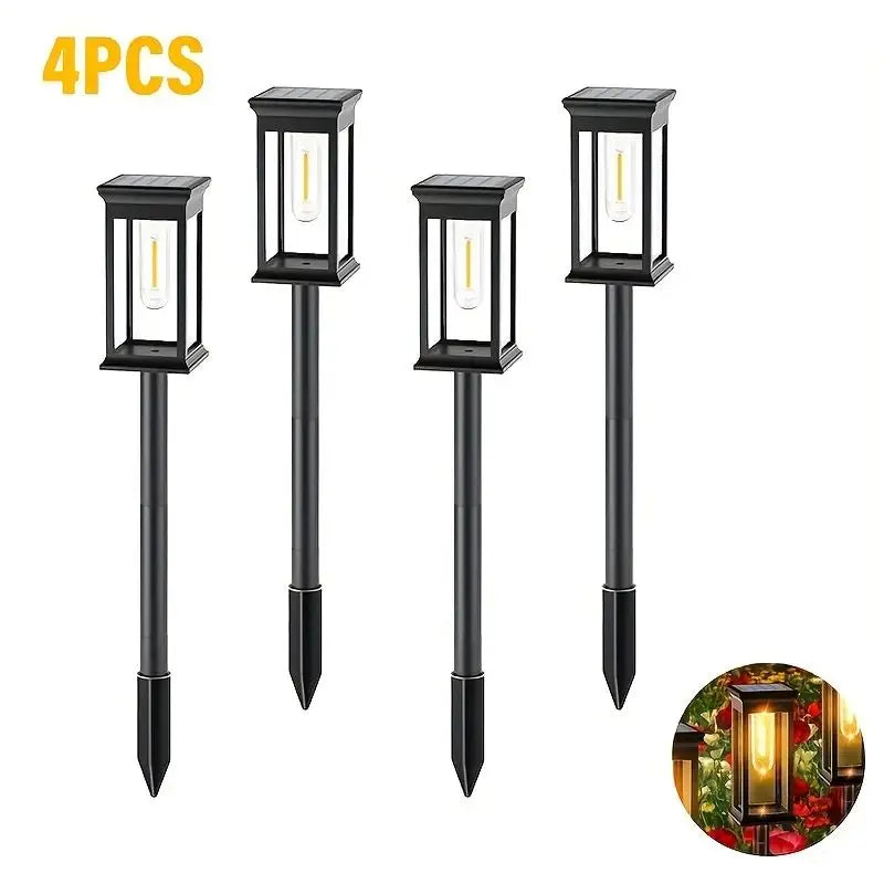 Four black solar path lights with warm glow illuminating an outdoor landscape.