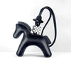 A black leather pony charm with a checkered silver and white buckle attached to a black strap.