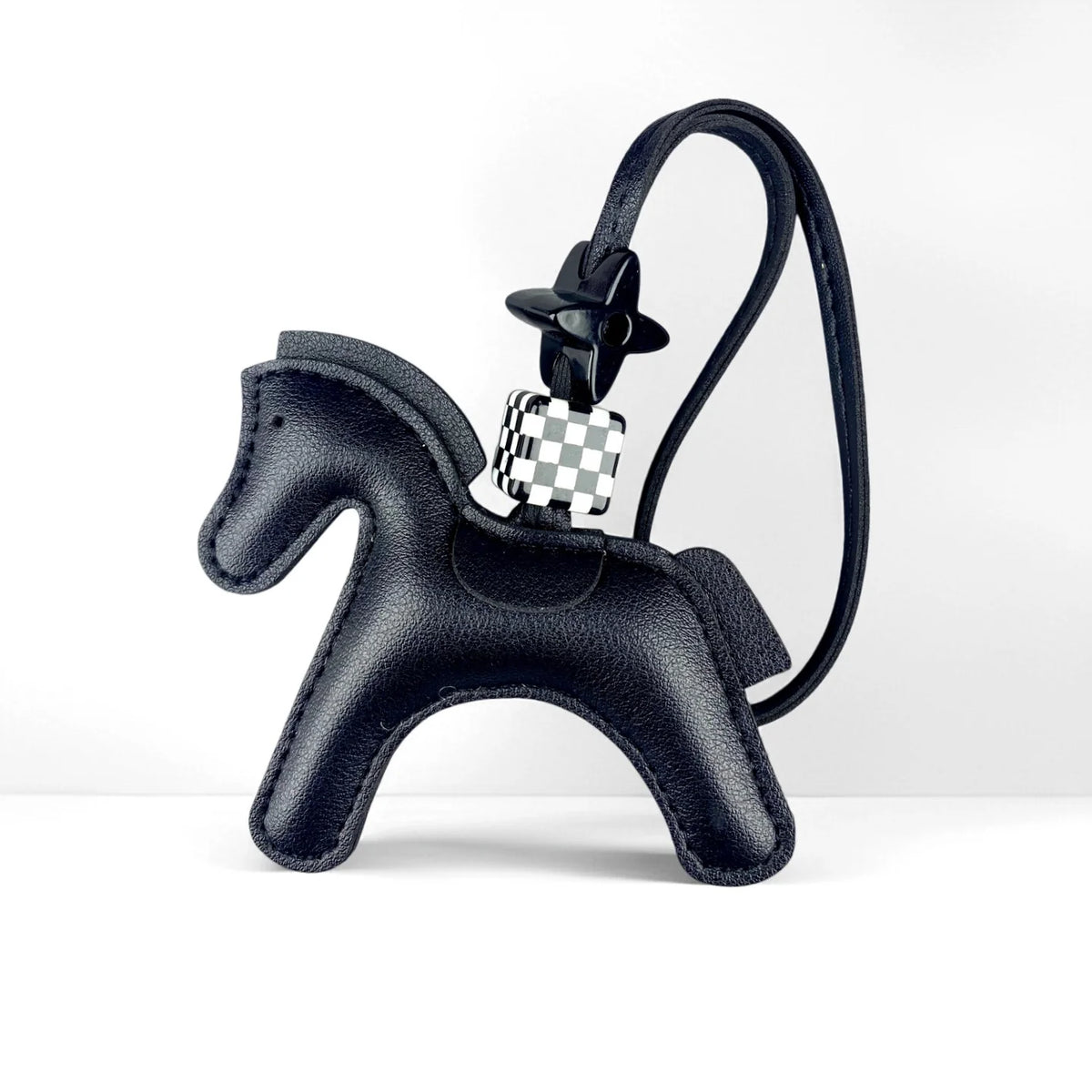 A black leather pony charm with a checkered silver and white buckle attached to a black strap.