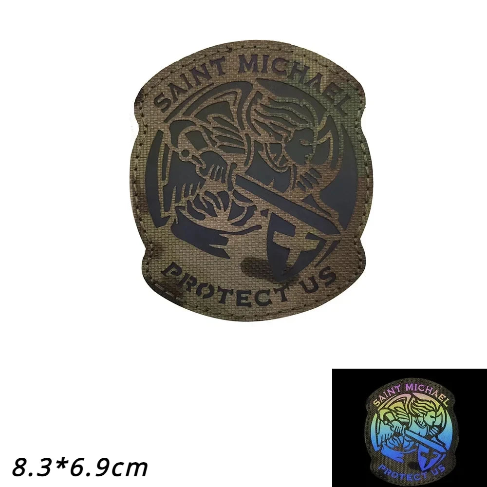 A dark brown reflective patch featuring the text SAINT MICHAEL PROTECT US and an archangel design.