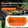 A silicone BBQ grease liner tray in orange is shown next to cooked meat on a grill.