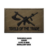 A dark olive embroidered patch with the text TOOLS OF THE TRADE on it.