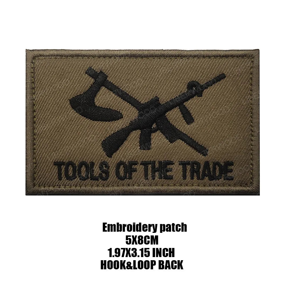 A dark olive embroidered patch with the text TOOLS OF THE TRADE on it.